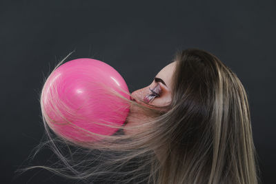 Portrait of woman with pink hair against black background