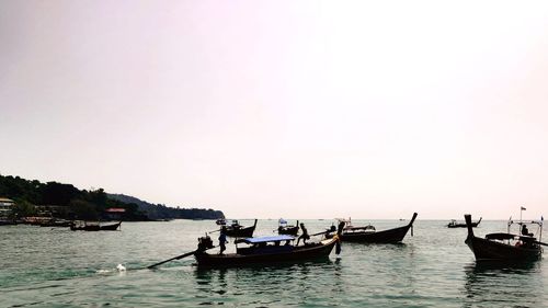 Boats in sea against clear sky