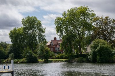 Trees by lake and buildings against sky