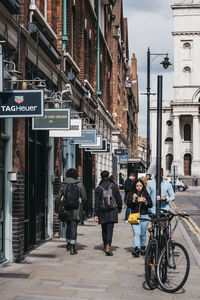People on street against buildings in city