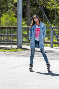 Full length of smiling young woman standing in city