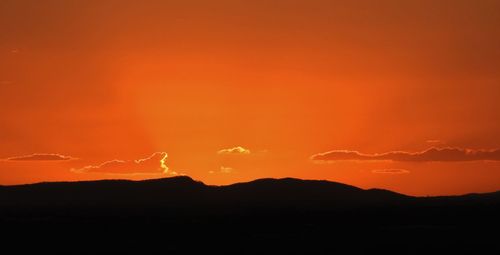 Silhouette landscape against dramatic sky during sunset