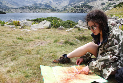 Young woman sitting on field by lake