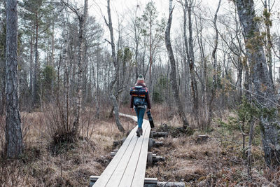 Woman walking in the forest with a guitar and backpack