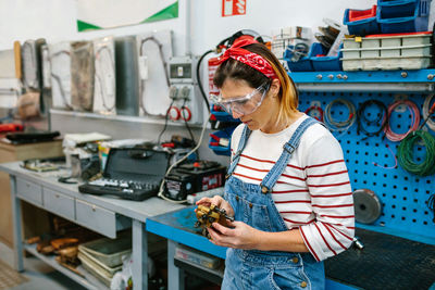 Mechanic woman checking caliper brake system in front of workbench