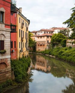 Buildings by river against sky in city