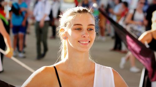 Confident smiling young woman looking away while standing on city street