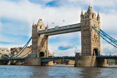 Tower bridge over thames river against cloudy sky