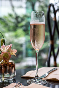 Close-up of wineglass on table and flowers in the vase