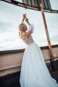 Midsection of woman with umbrella standing against sky