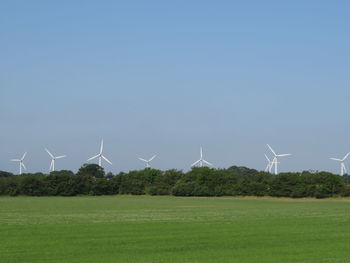 Wind turbines on field against clear sky