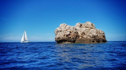 Sailboat in sea against clear blue sky