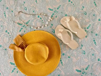 Directly above shot of hat and flip-flop and necklace on table