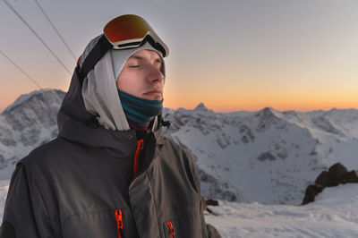 Man in ski goggles against the backdrop of snow-capped mountains and blue sky during sunset. eyes