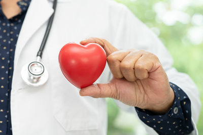 Midsection of doctor holding heart shape