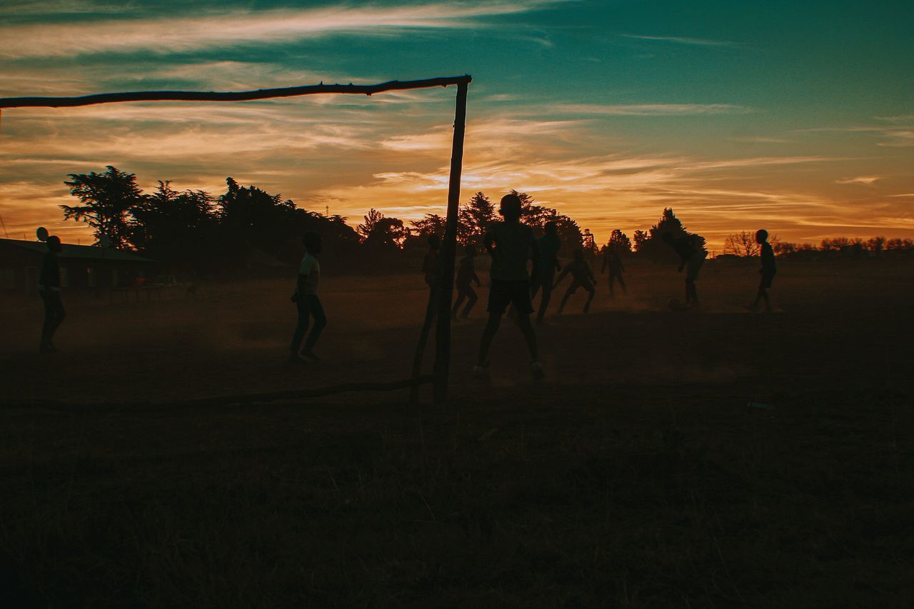 SILHOUETTE PEOPLE ON FIELD AT SUNSET