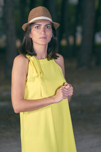 Portrait of woman standing against trees on field