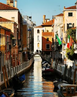 Boats in canal amidst buildings in city against sky