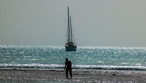 Man standing on beach against clear sky