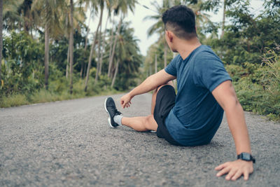 Young man sitting on road in city