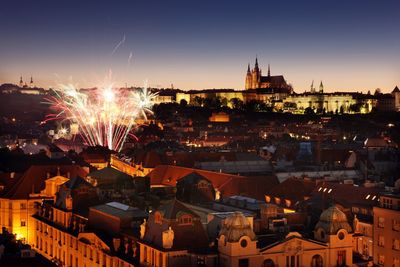 Illuminated fireworks amidst cityscape at dusk