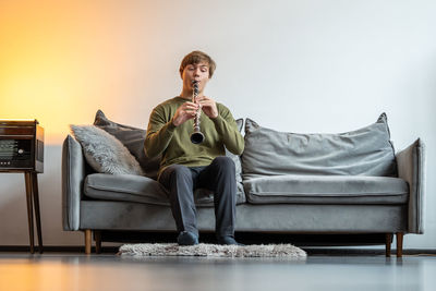 Young man using mobile phone while sitting on sofa at home