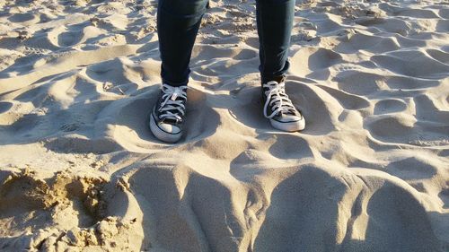 Low section of person standing on sandy beach