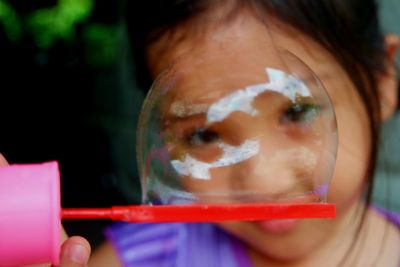 Close-up of cute girl with bubble wand at home