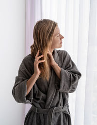 Womens health. spa and wellness. happy young woman applying hair mask standing next to the window