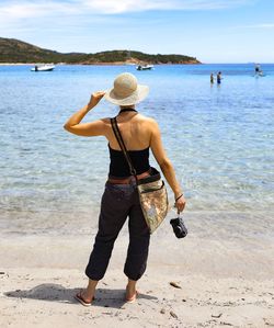 Rear view of woman standing at beach against sky