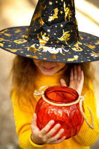 Smiling girl wearing hat and holding container outdoors