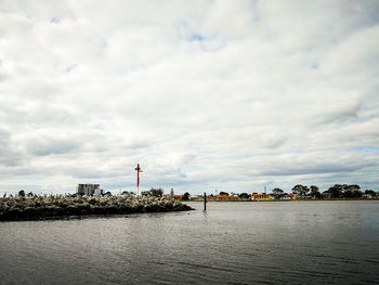 Scenic view of river by buildings against sky