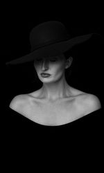 Portrait of woman wearing hat against black background