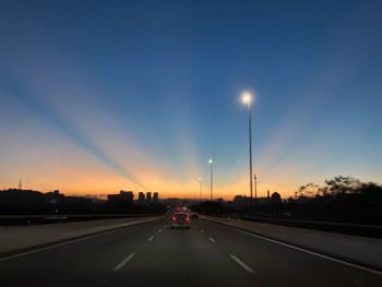 Cars on road against sky during sunset