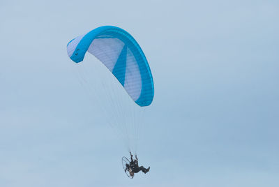 Low angle view of person powered paragliding against sky