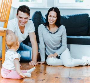 Happy parents playing with baby girl at home