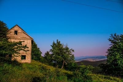 House on field against clear blue sky