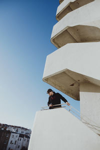 Low angle portrait of man against building against clear sky