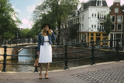 Woman standing by canal in city