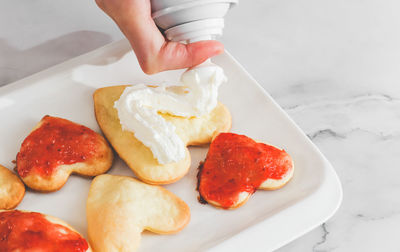 Not perfect freshly baked heart cookies in a white plate with strawberry jam .