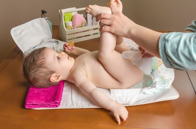 Woman changing diaper of baby girl at home