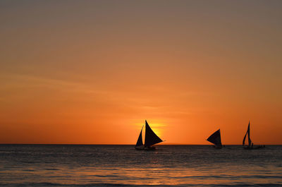 Silhouette boat in sea against sky during sunset