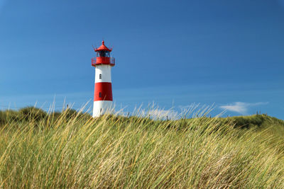 Lighthouse on field against blue sky