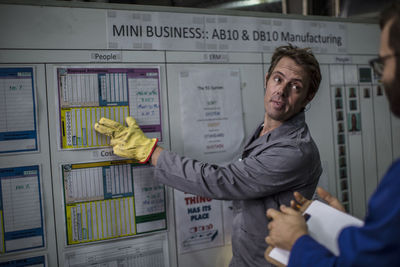 Two men discussing on white board in factory