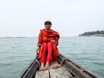 Portrait of man sitting on boat in sea against sky