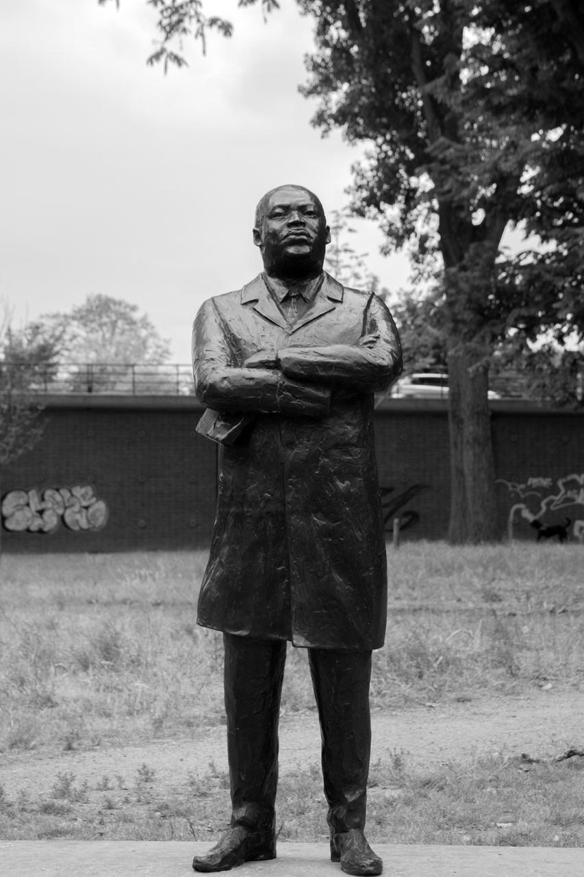 FULL LENGTH PORTRAIT OF MAN STANDING ON FIELD AGAINST TREES