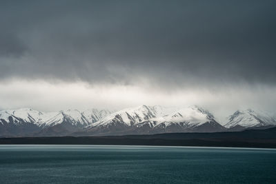 Gloomy landscape of new zealand southern alps and lake pukaki with blue sky and clouds.