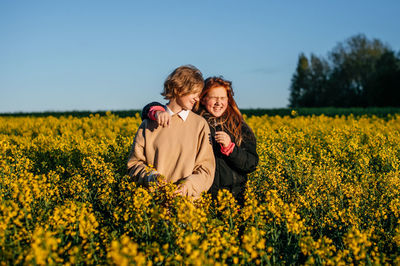 Portrait of woman standing amidst yellow flowering plants on field