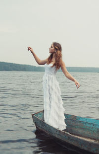 Young woman standing on boat in sea against sky