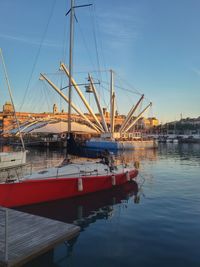 Boats moored at harbor against clear blue sky